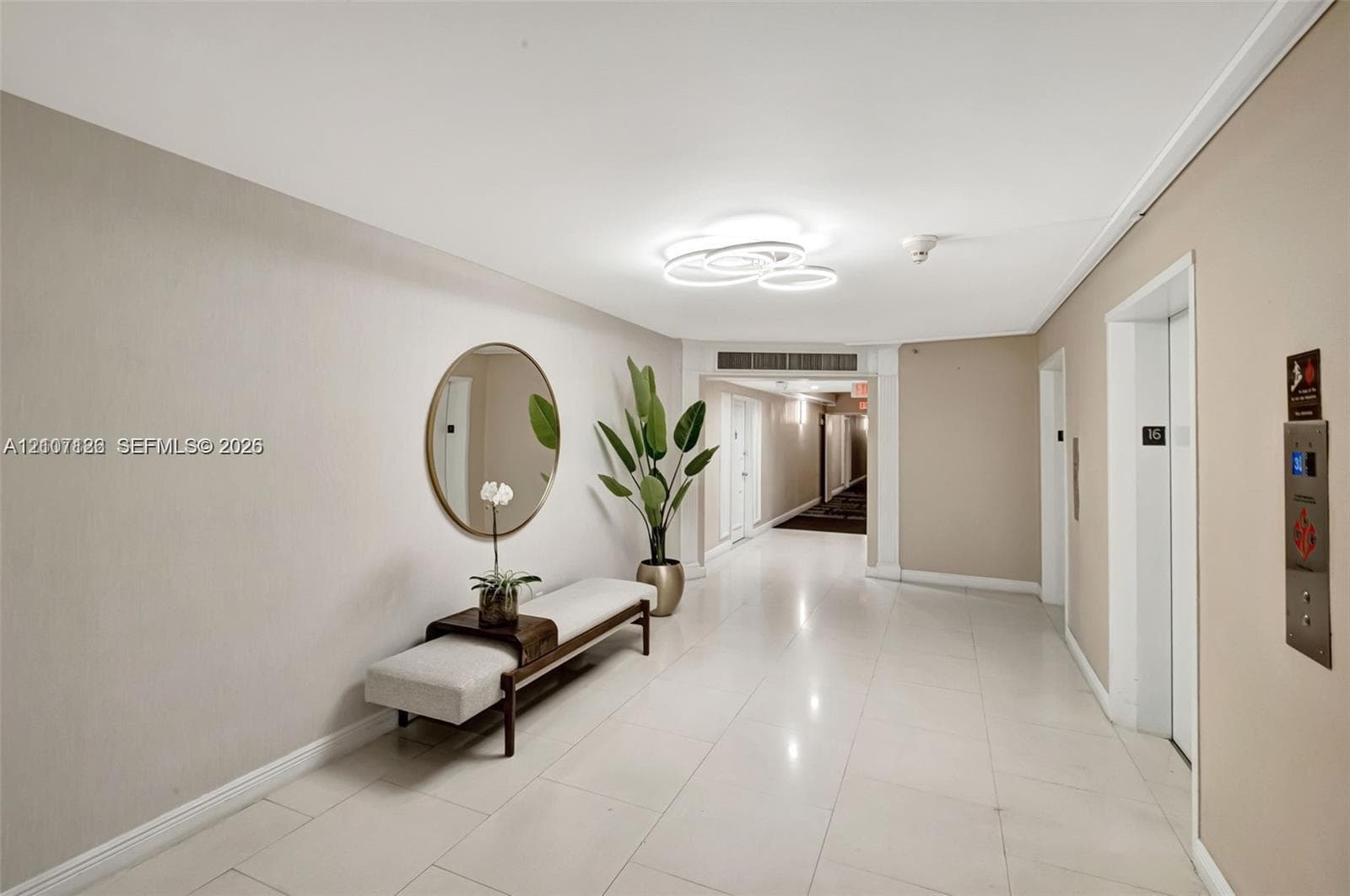 Contemporary lobby featuring polished tile flooring, modern circular flush-mount lighting, and neutral wall finishes