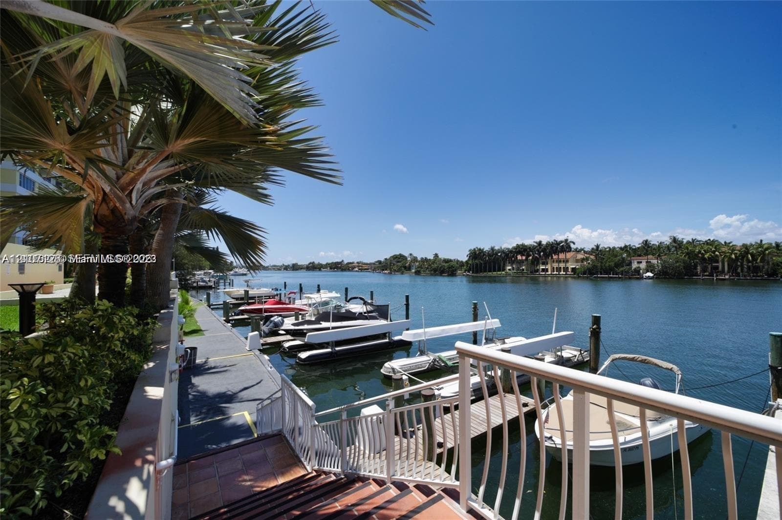 Waterfront property featuring a private boat dock, tiled stair access, and mature palm trees