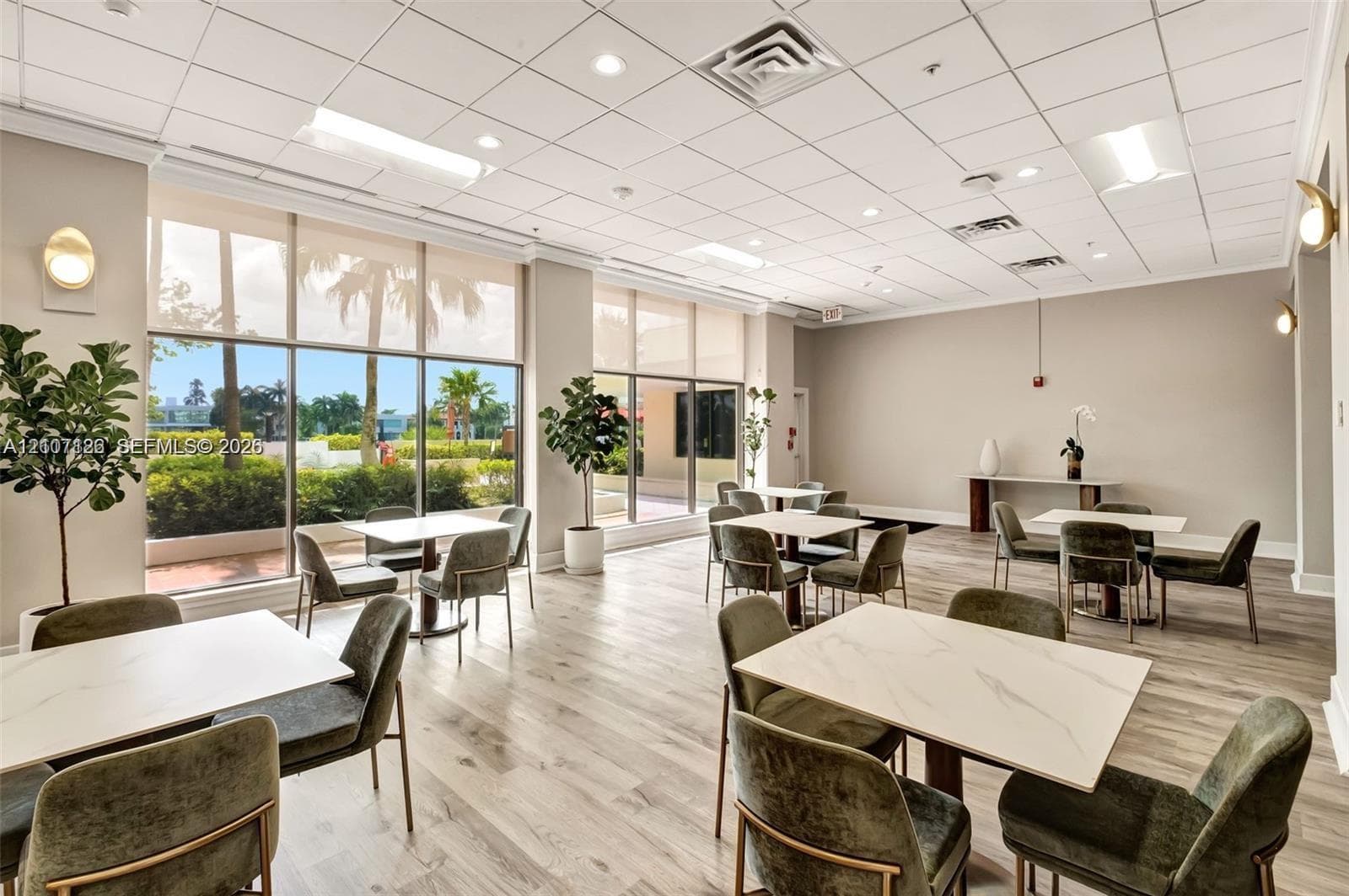 Open-concept interior space featuring wood-finish flooring, floor-to-ceiling windows, recessed lighting, and wall-mounted sconces