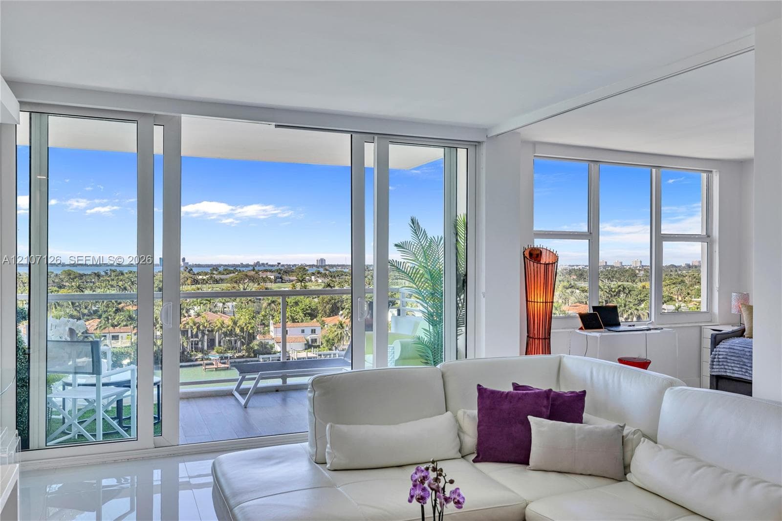 Floor-to-ceiling glass sliding doors, private balcony with glass railing, expansive windows, polished tile flooring, and open-plan interior