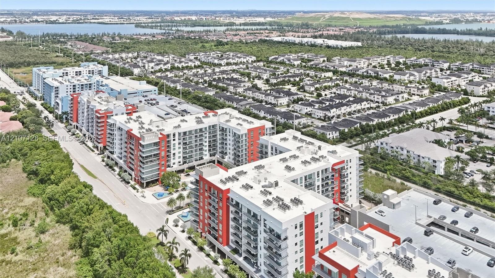 Aerial perspective of a multi-story residential complex featuring modern architecture, structured parking facilities, balcony units, and landscaped grounds