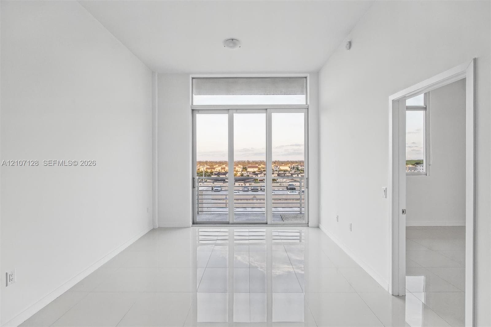 Interior space featuring 24x24 tile flooring, floor-to-ceiling glass sliding doors, and a private balcony with horizontal metal railings
