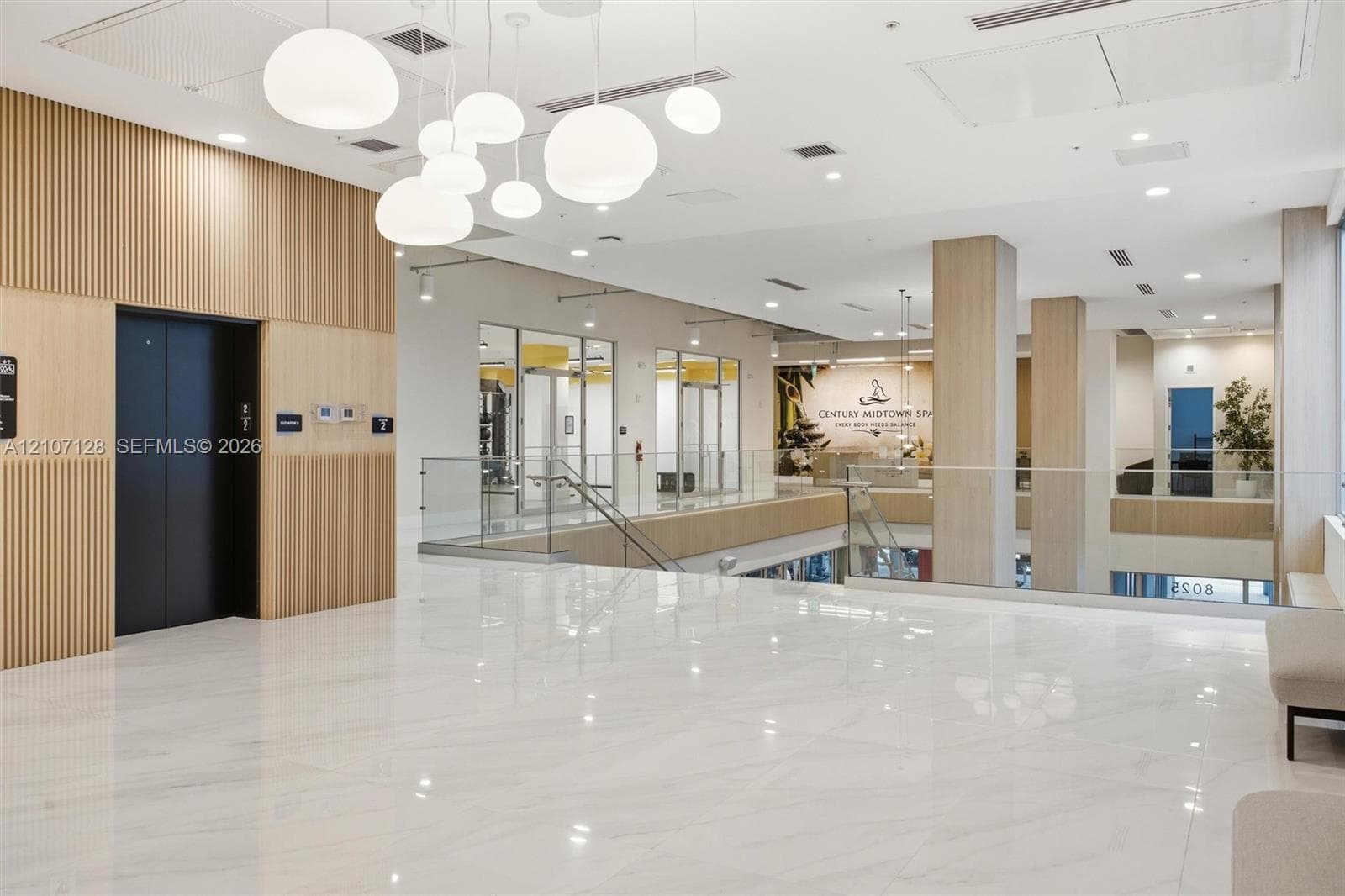 Polished stone flooring, vertical wood-slat wall paneling, multi-globe pendant lighting, glass panel railings, and recessed ceiling lighting