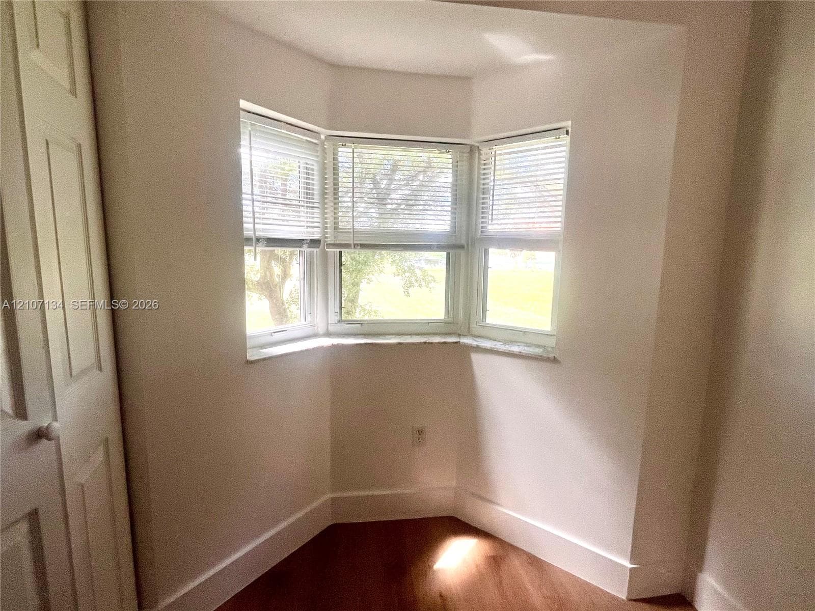 Bay window featuring tripartite casement windows with stone-finish sills, wood-finish flooring, and built-in closet with multi-panel door