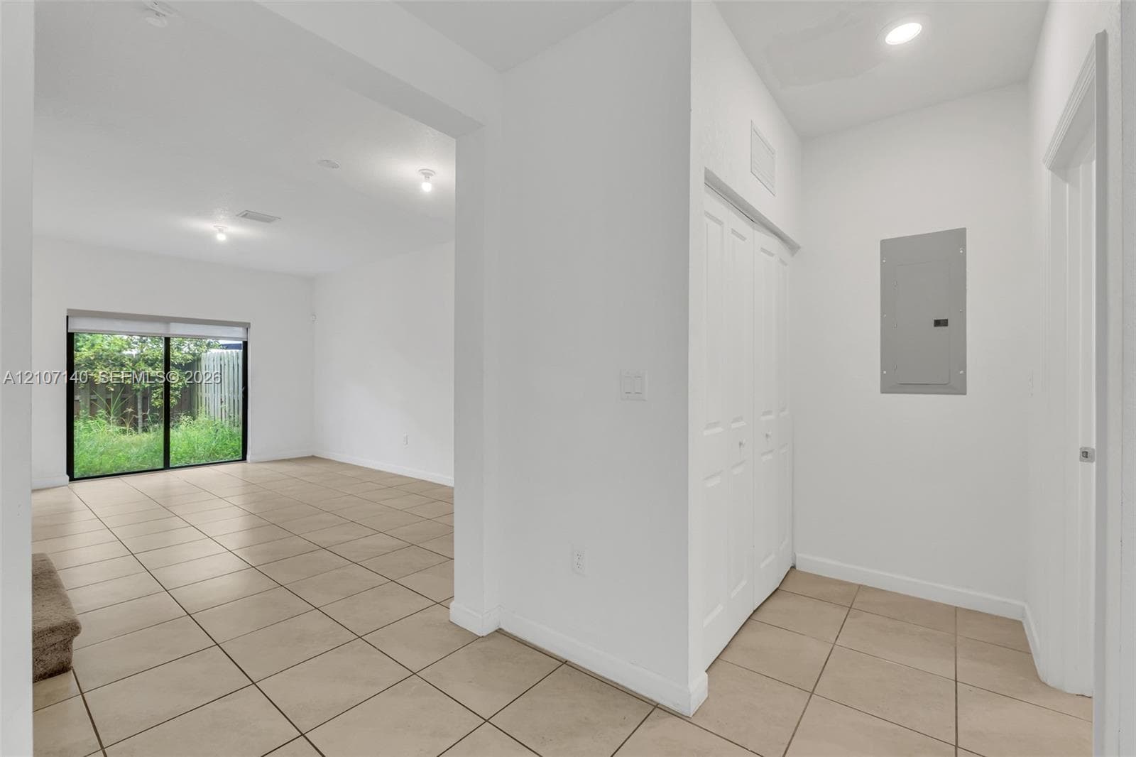 Neutral-toned ceramic tile flooring, sliding glass door, white bifold closet doors, and recessed lighting
