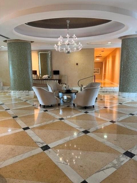 Grand entrance hall featuring a recessed circular ceiling, polished stone flooring with geometric inlays, decorative mosaic-tiled columns, and a multi-tiered crystal chandelier
