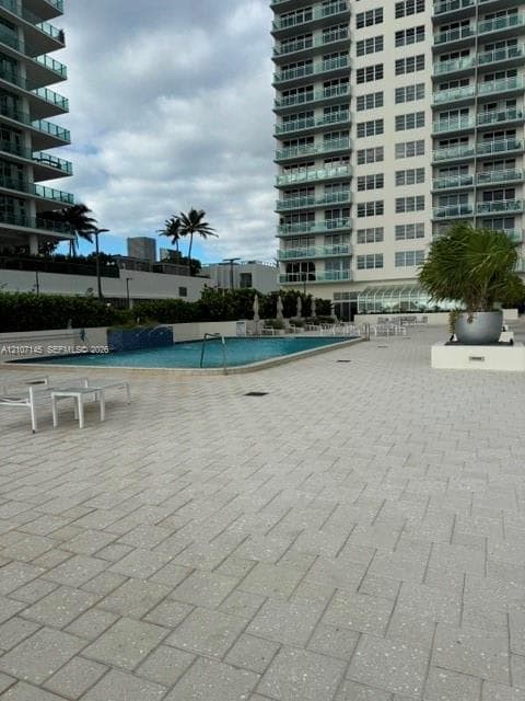 Outdoor pool deck featuring a tiled hardscape, mosaic-accented water feature, and integrated landscape planters