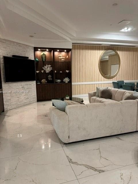 Large-format stone-style flooring, stacked stone wall accent, built-in recessed shelving with integrated lighting, and crown molding