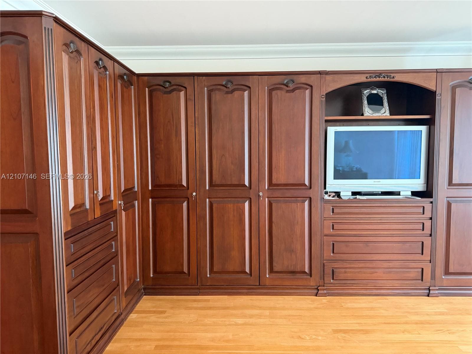Custom built-in corner cabinet with ornate wood trim, Venetian plaster walls, intricate metal wall-mounted sconce, and tile flooring