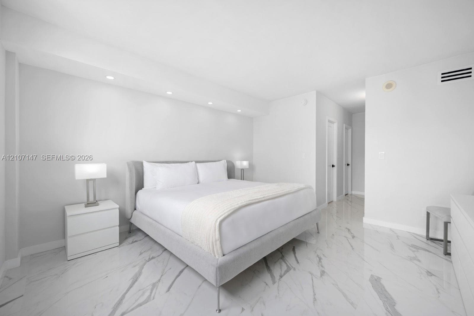 Neutral-toned interior featuring polished stone-finish flooring with veining, recessed cove lighting, and smooth-finish walls