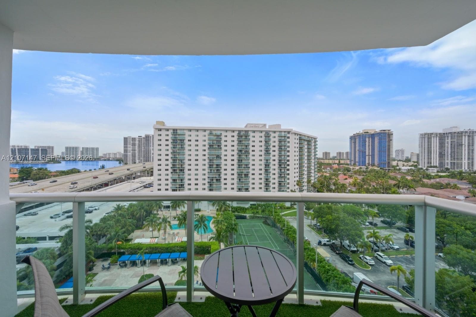 Private balcony featuring a glass-panel railing and synthetic turf flooring