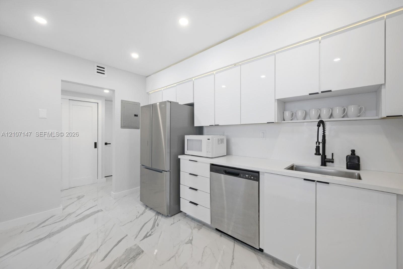 Kitchen featuring white high-gloss cabinetry, stainless steel appliances, solid-surface countertops, a matte black pull-down faucet, and polished stone-finish tile flooring