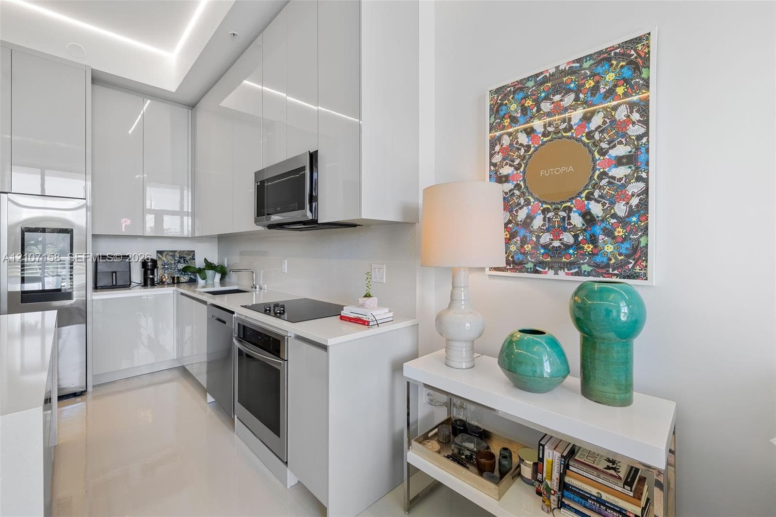 Sleek high-gloss cabinetry, stainless steel appliances, solid-surface countertops, recessed cove lighting, and polished stone-finish flooring