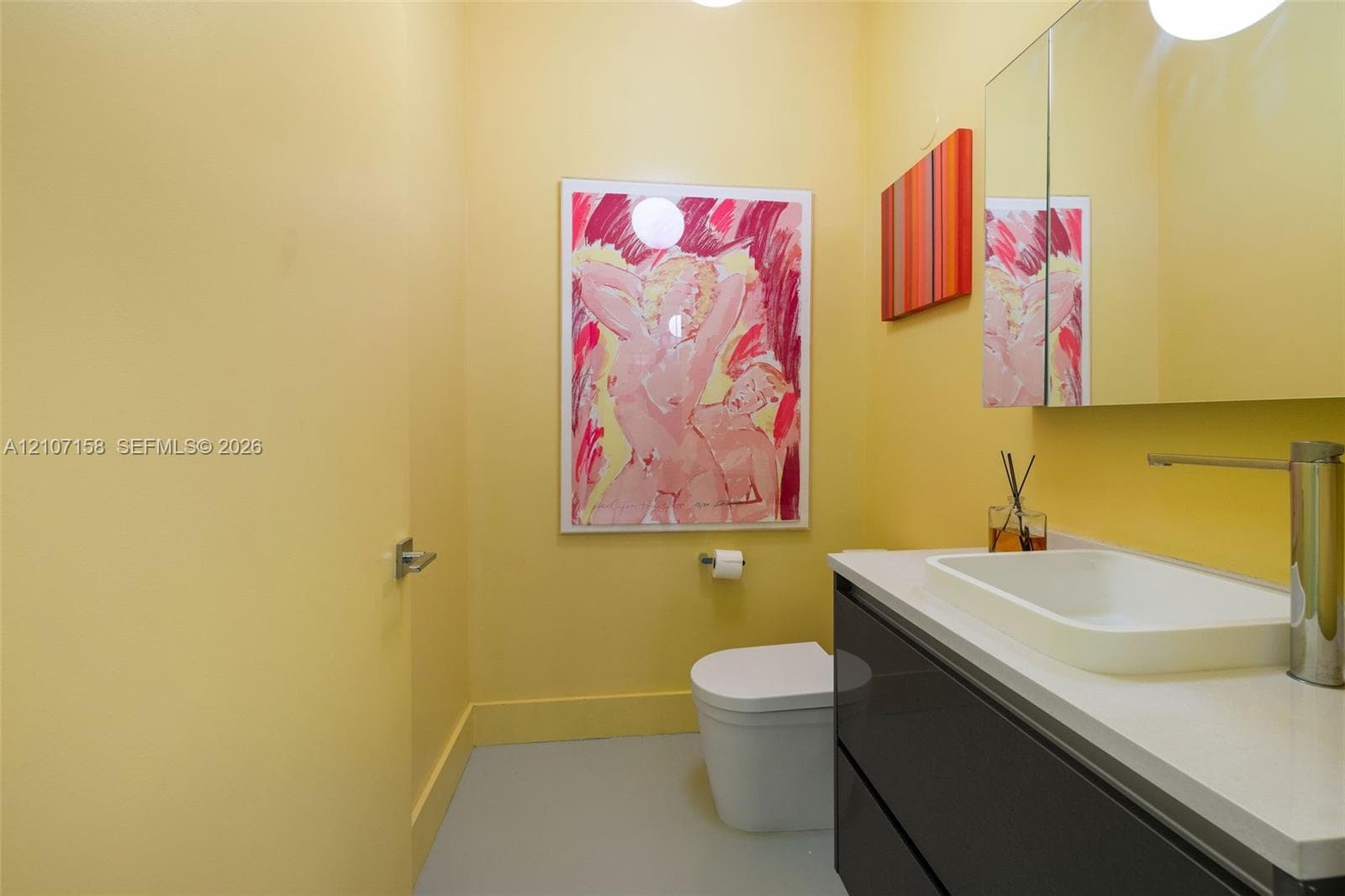 Modern floating vanity with a white countertop, vessel sink, tall metal faucet, and two-drawer dark cabinetry, featuring a large wall-mounted mirrored medicine cabinet and a wall-mounted toilet