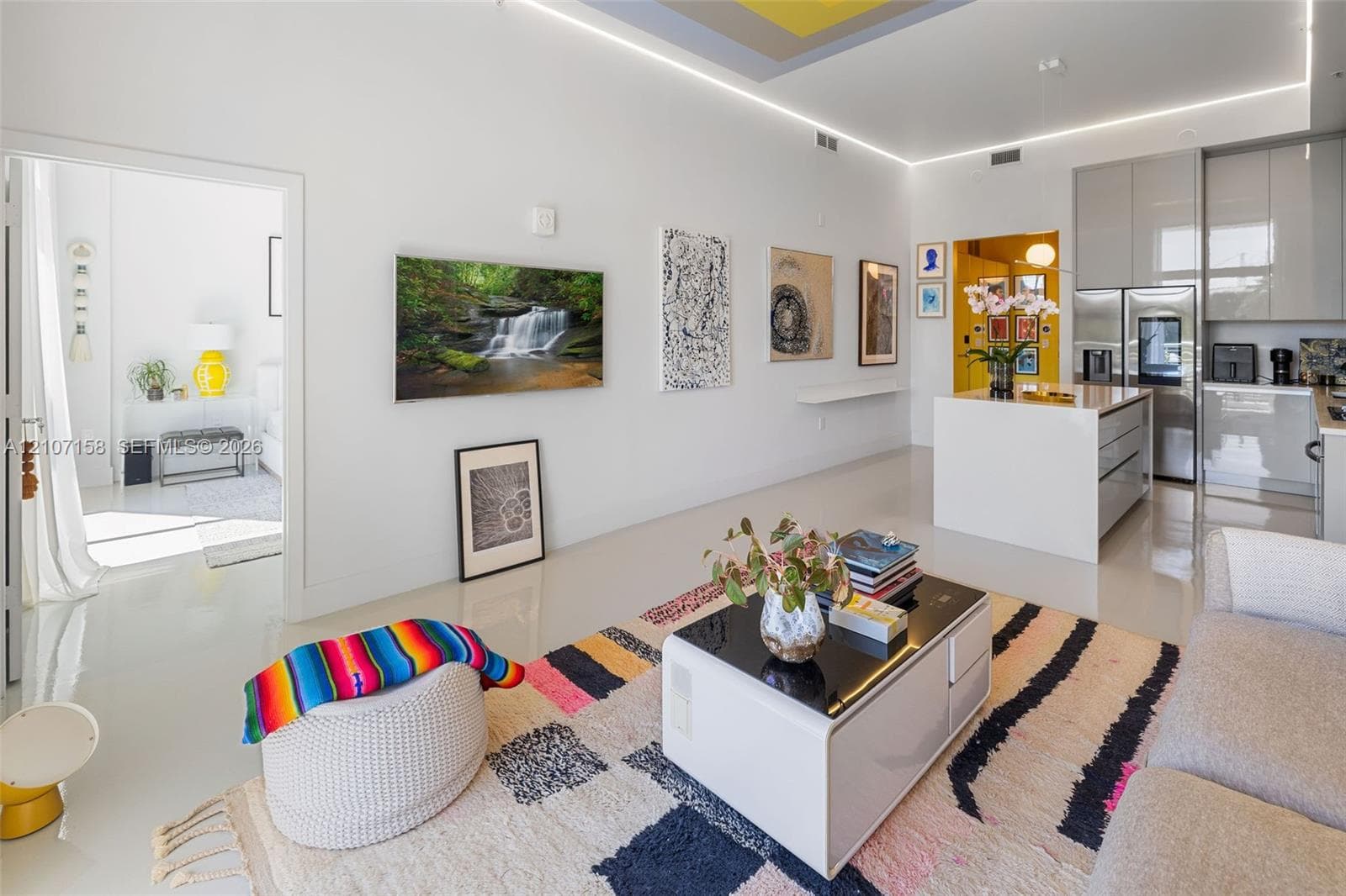 Open-concept living space featuring high-gloss flooring, recessed linear perimeter lighting, a kitchen island with stone countertop, and high-gloss cabinetry