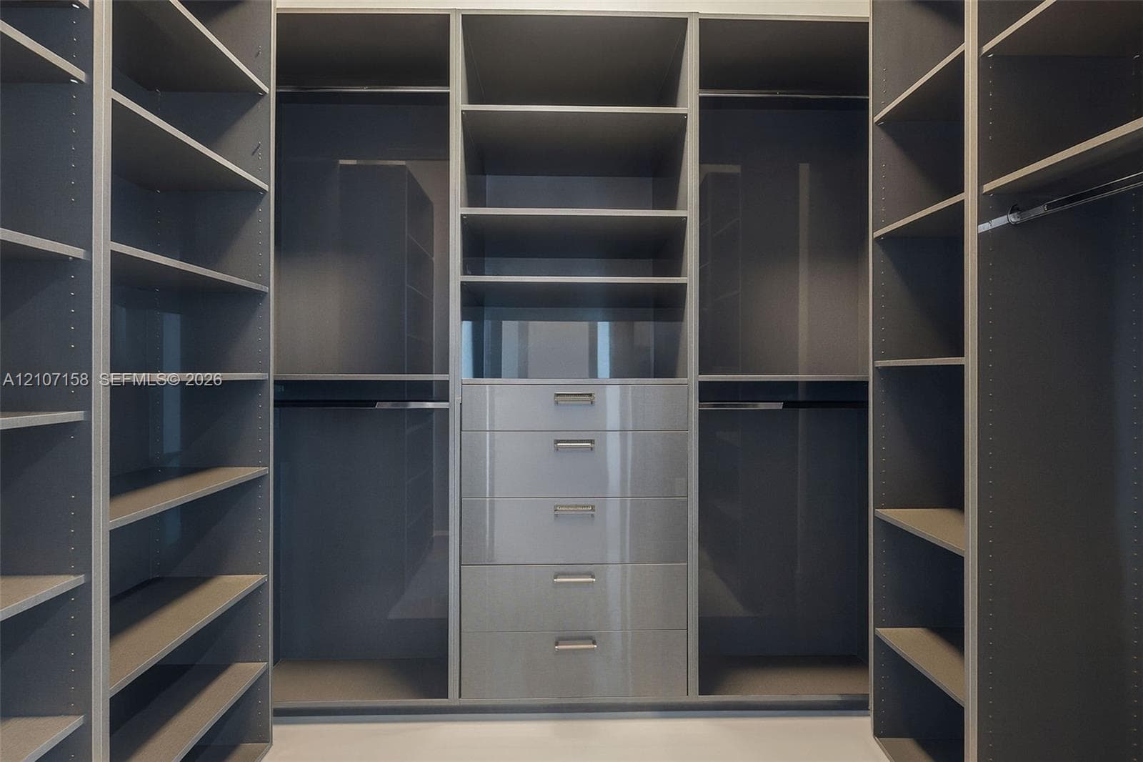 Custom built-in storage system featuring matte-finish shelving, integrated hanging rods, and a central bank of five soft-close drawers with metallic pulls