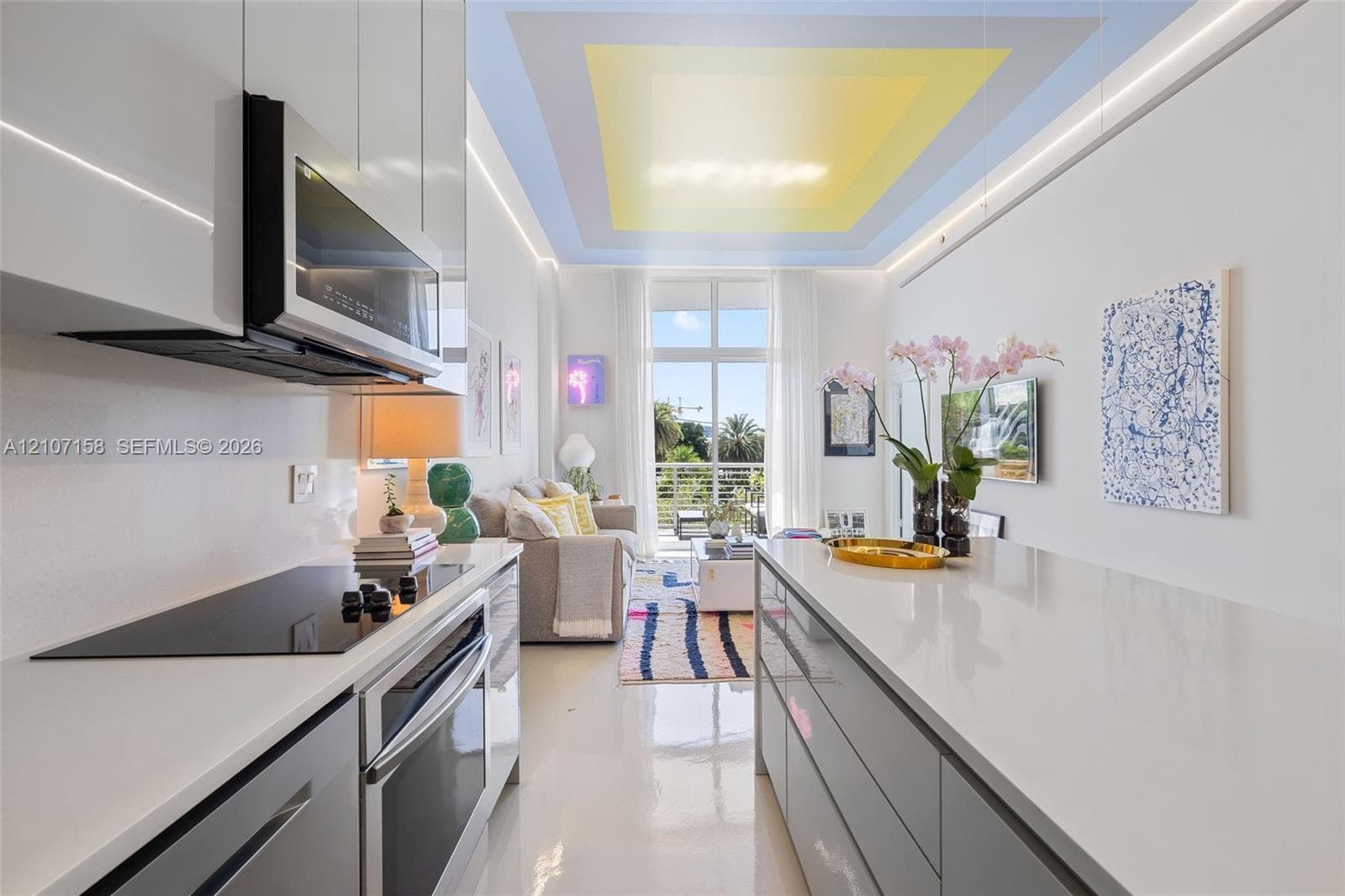Modern kitchen featuring high-gloss cabinetry, stone-surface countertops, built-in stainless steel appliances, and a recessed ceiling design with perimeter lighting