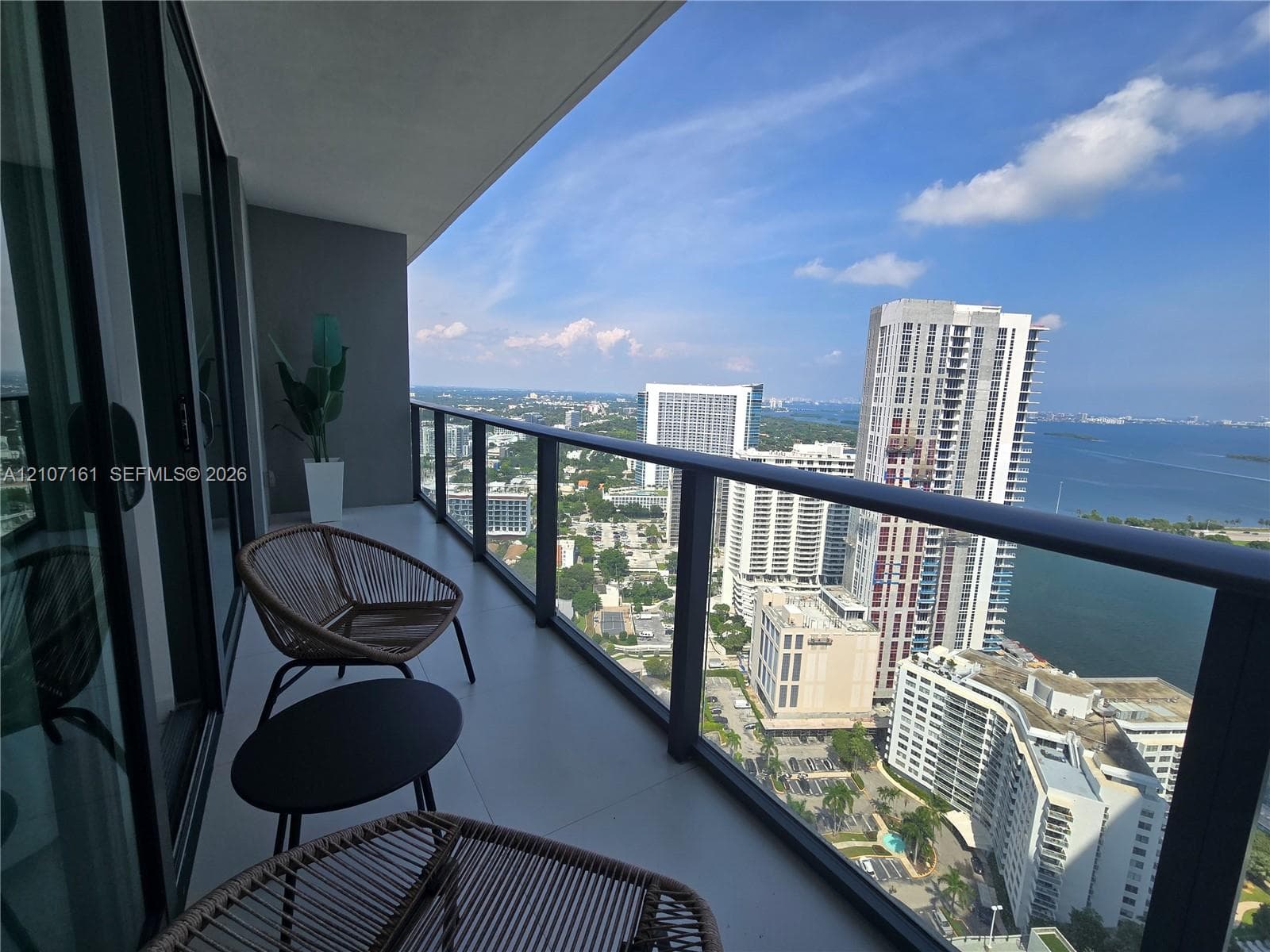 Covered balcony featuring concrete flooring and a sleek glass railing with a dark metal frame