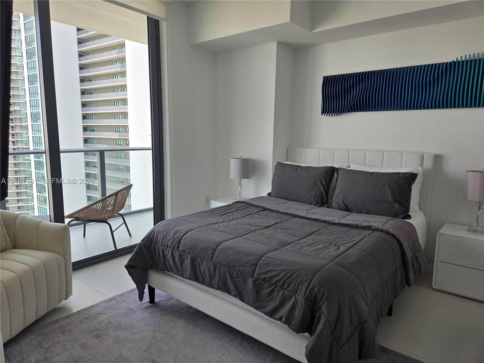 Floor-to-ceiling windows, private balcony, neutral-tone large-format tile flooring, and clean-lined architectural walls