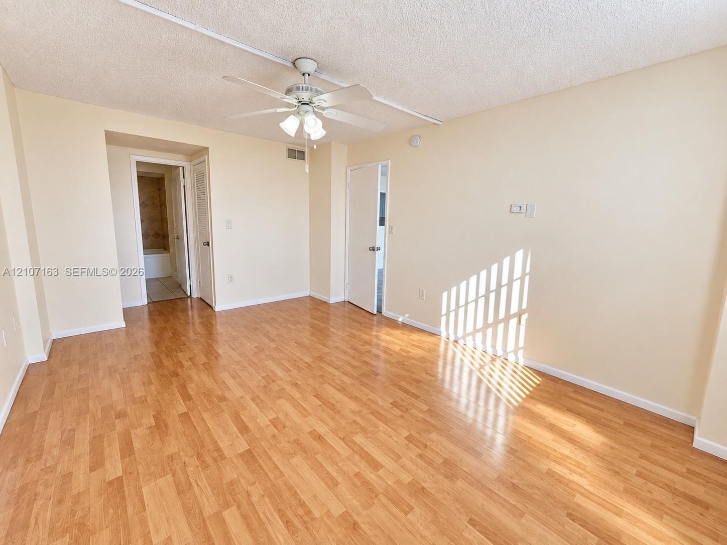 Interior space featuring wood-finish flooring, a ceiling fan with integrated lighting, and white paneled doors