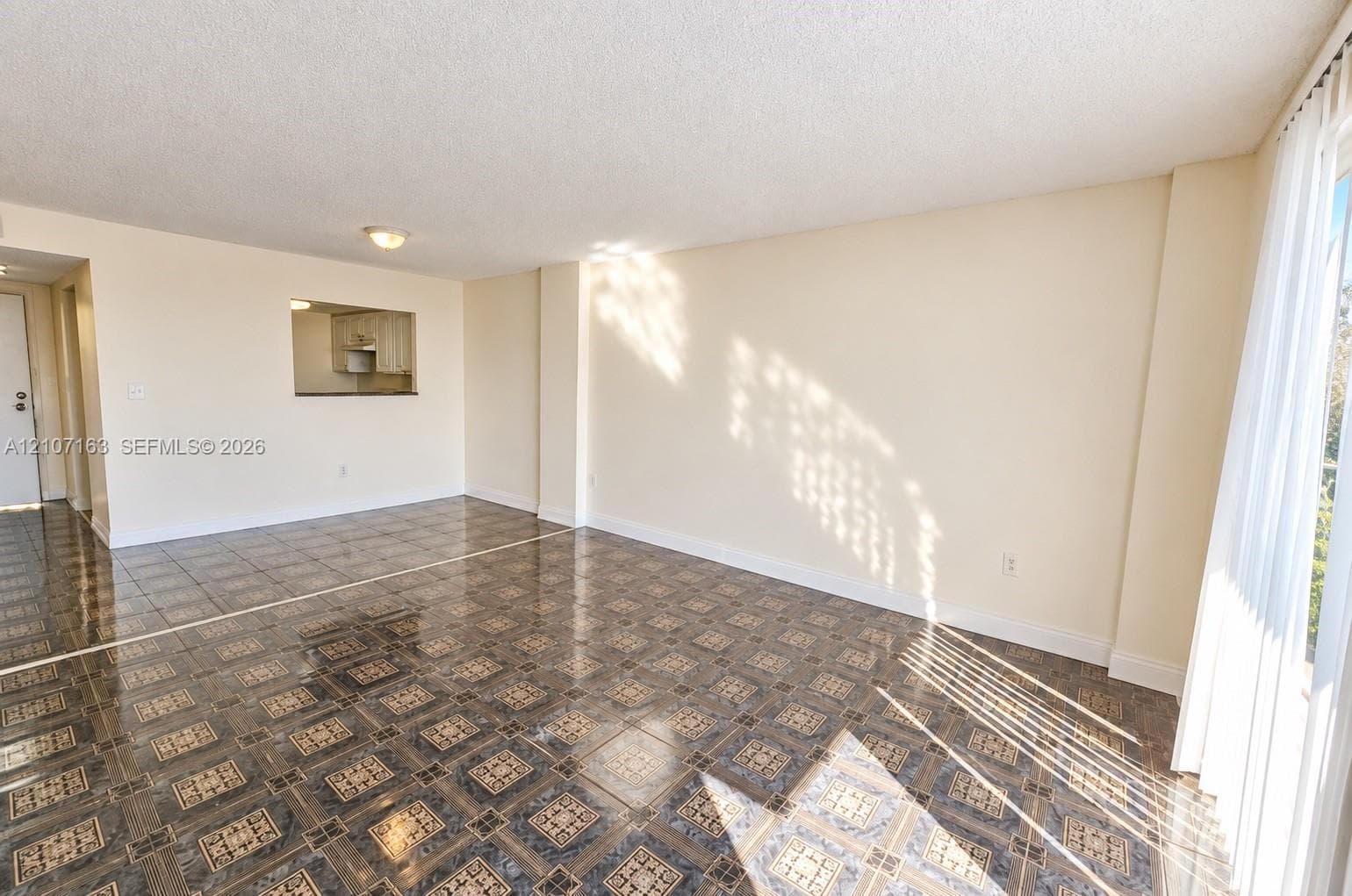 Interior space featuring patterned tile flooring, a pass-through opening, and floor-to-ceiling windows