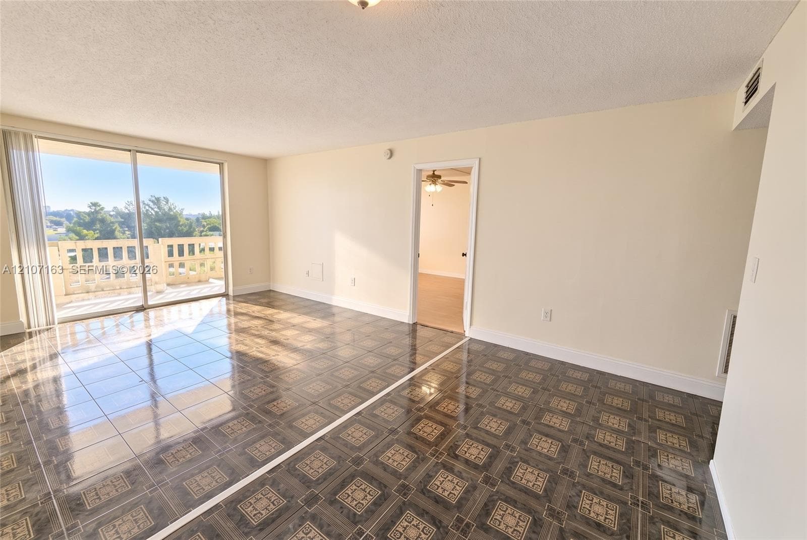 Open-concept living space featuring patterned tile flooring and glass sliding doors to a concrete balcony