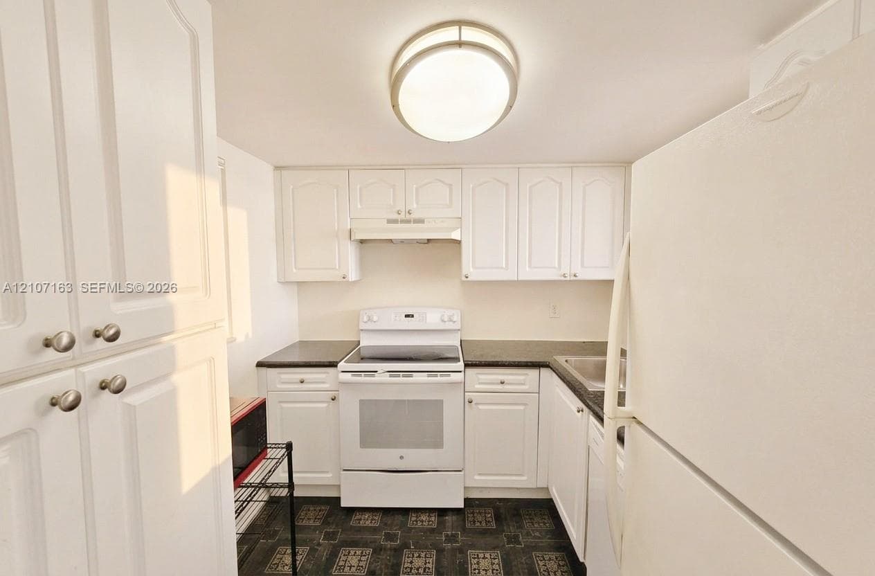 Kitchen featuring white cabinetry, solid-surface countertops, a white range, a stainless steel sink, and a flush-mount ceiling light fixture