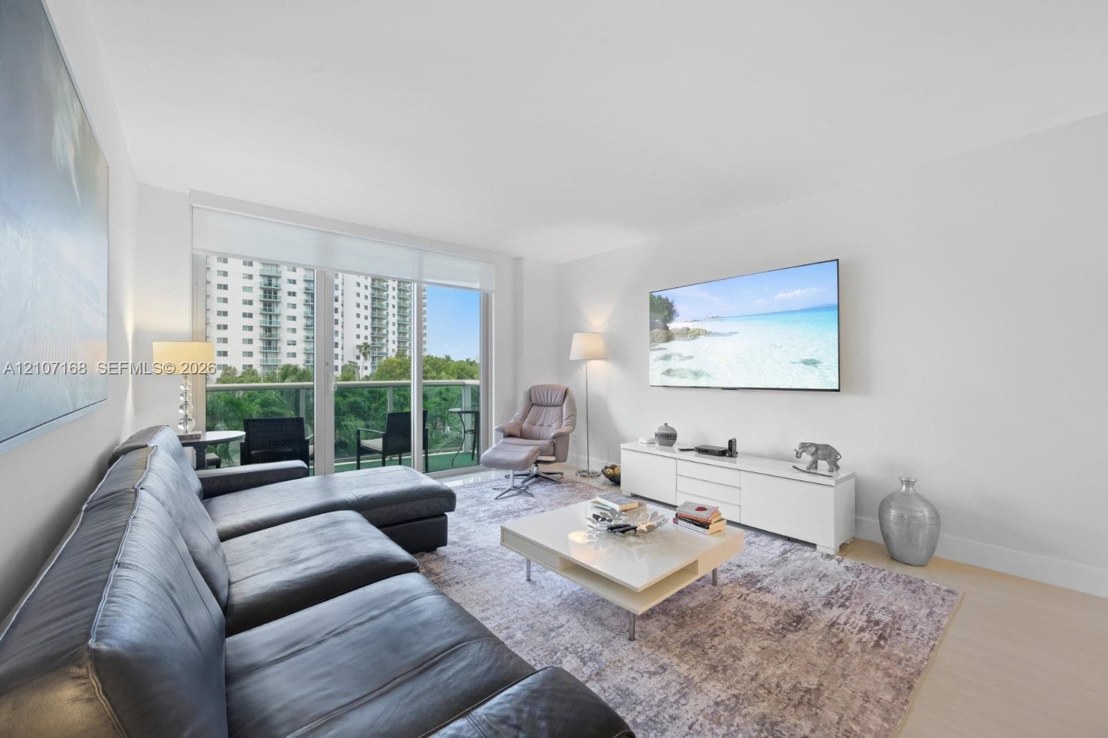 Living area featuring floor-to-ceiling glass sliding doors, private balcony access, and light-toned wood-finish flooring