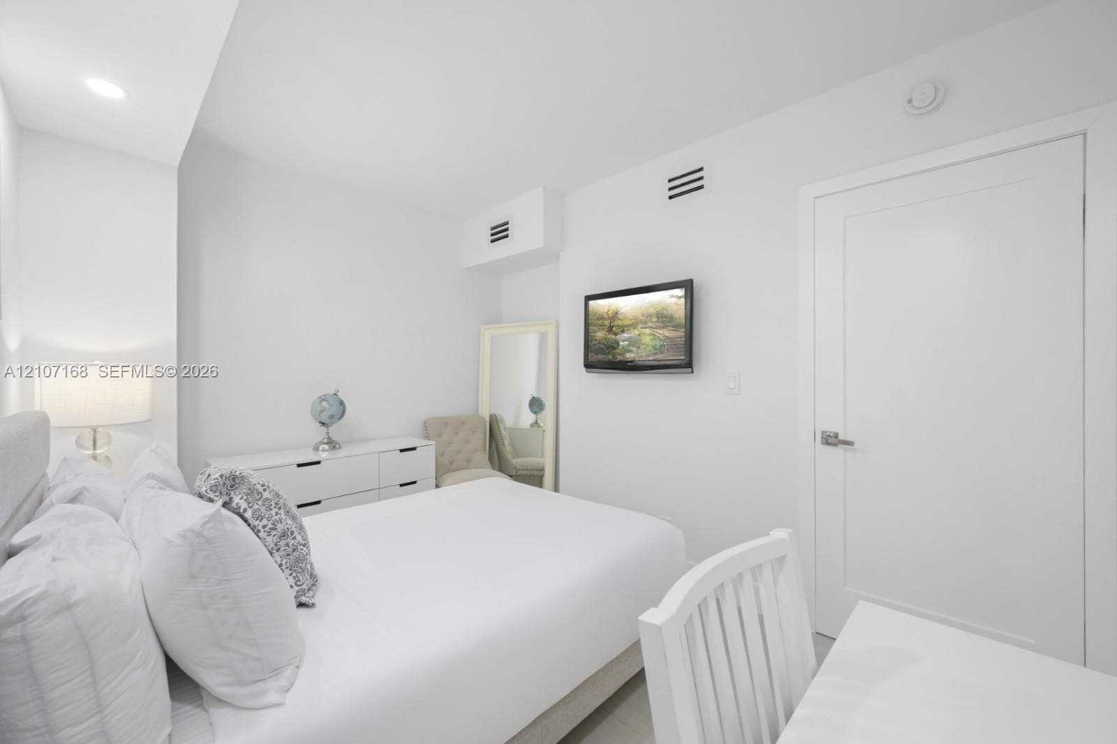 Neutral-toned interior featuring crisp white walls, recessed ceiling lighting, and a solid-core interior door with modern hardware