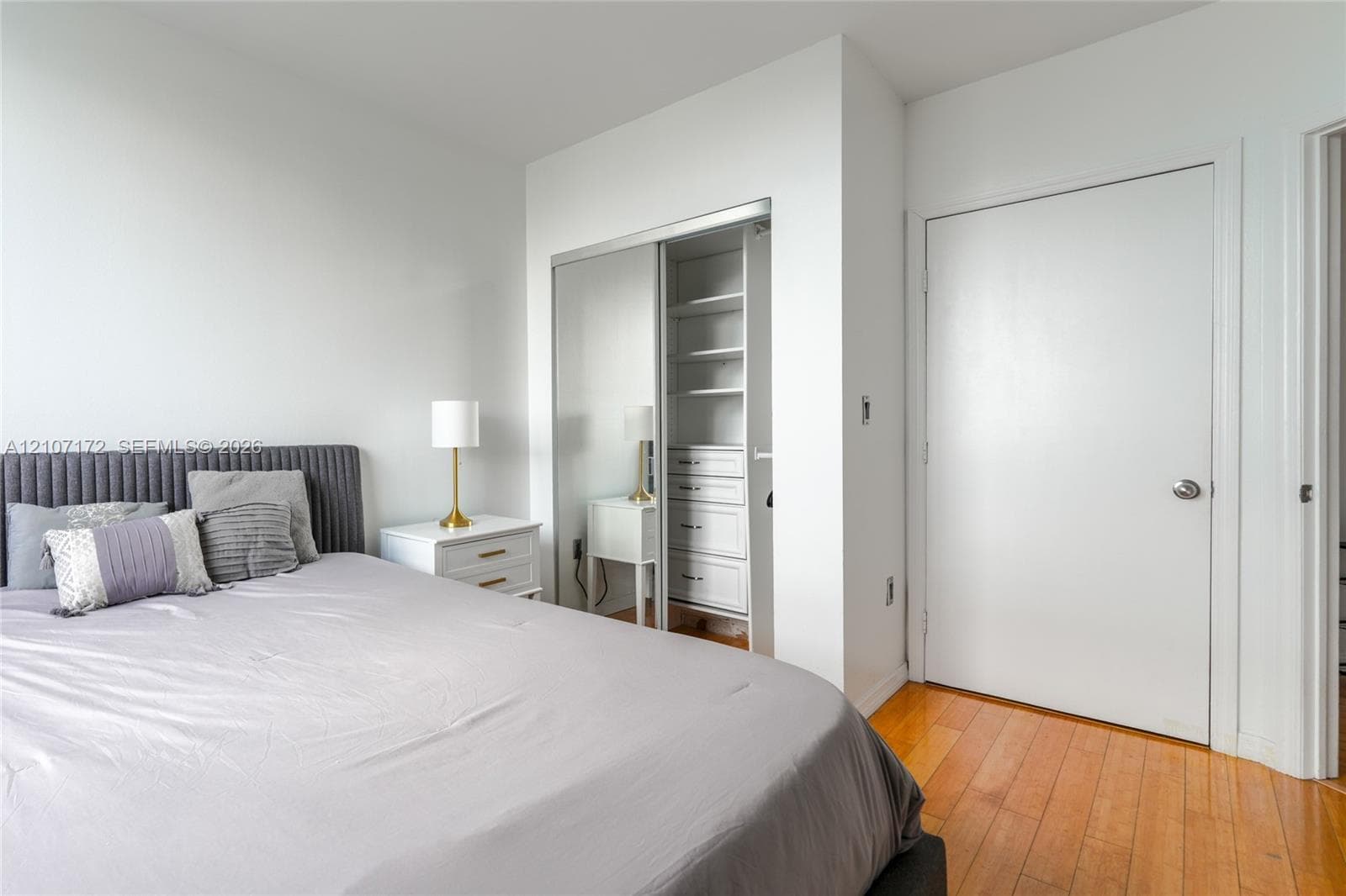 Wood-finish flooring, sliding mirror closet doors, and built-in closet shelving featuring integrated drawers