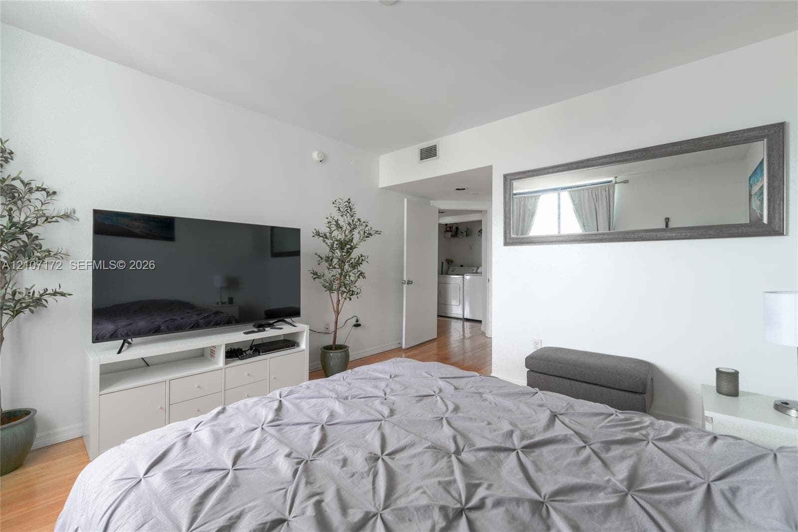 Wood-finish flooring and wall-mounted rectangular mirror with a dark frame