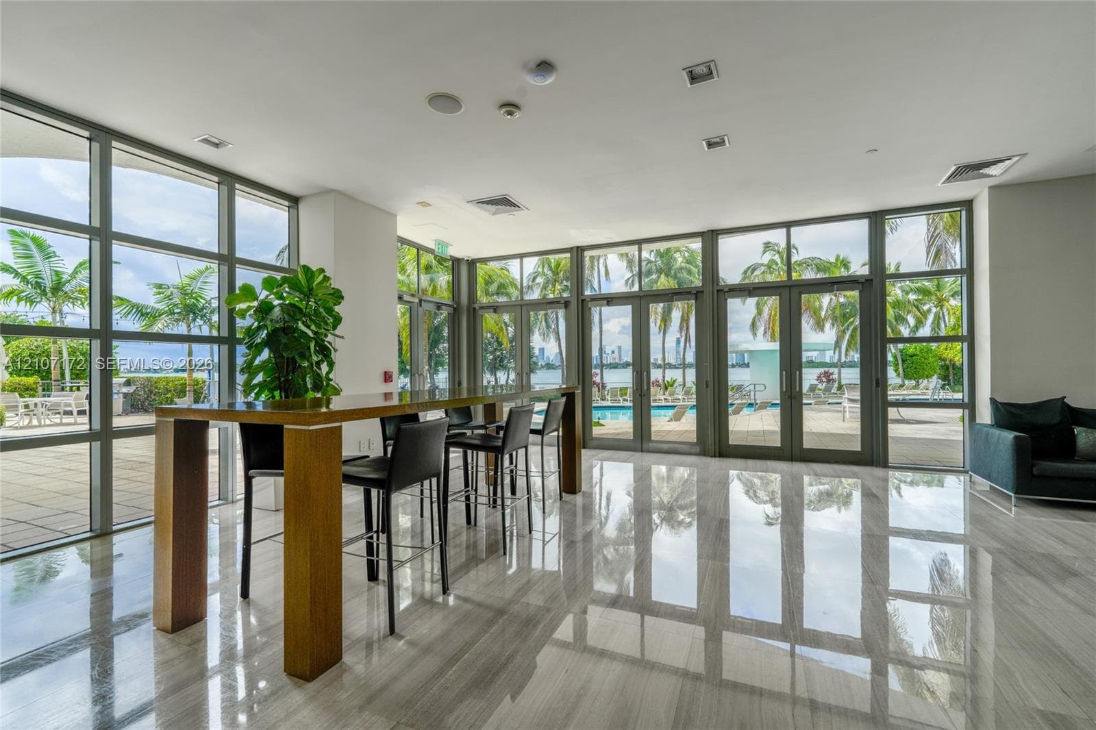 Floor-to-ceiling windows, polished stone flooring, and multiple glass-paned doors featuring metal frames