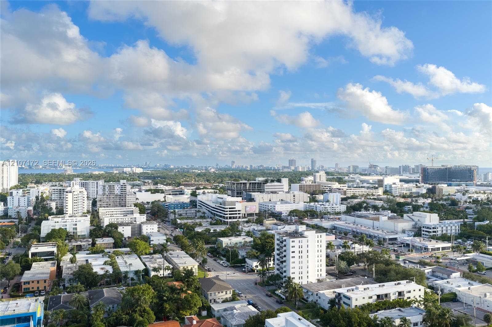 Aerial perspective featuring an expansive cityscape, horizon-spanning skyline, and distant coastal waters under a vast sky