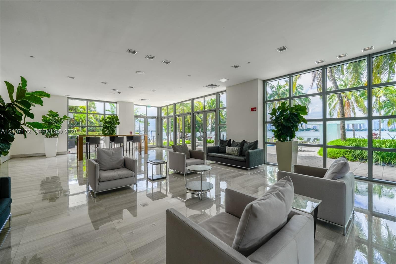 Open-concept interior featuring floor-to-ceiling glass wall panels, polished large-format tile flooring, and recessed ceiling lighting