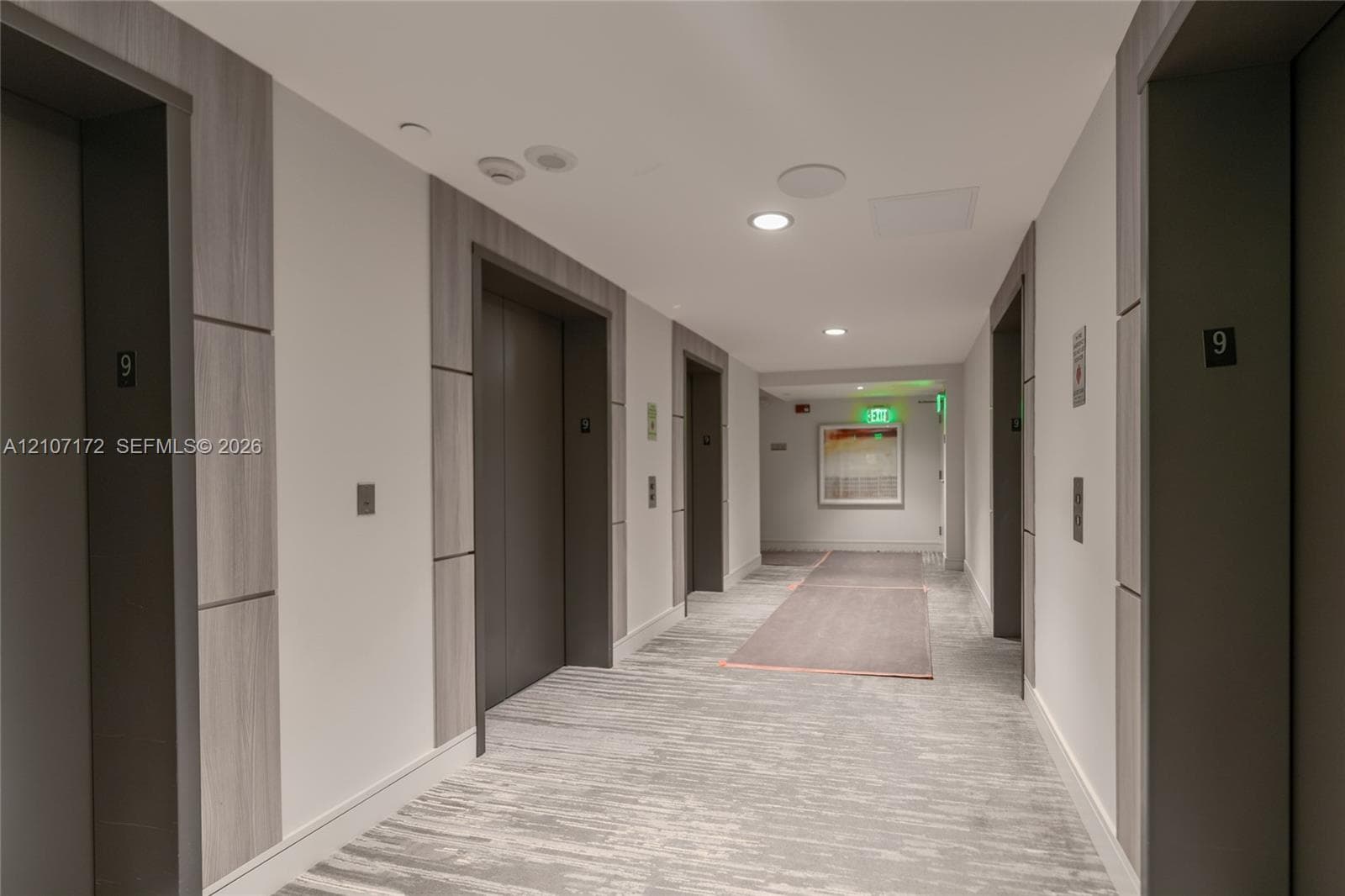 Elevator lobby featuring metallic elevator doors, wood-finish wall paneling, and recessed lighting