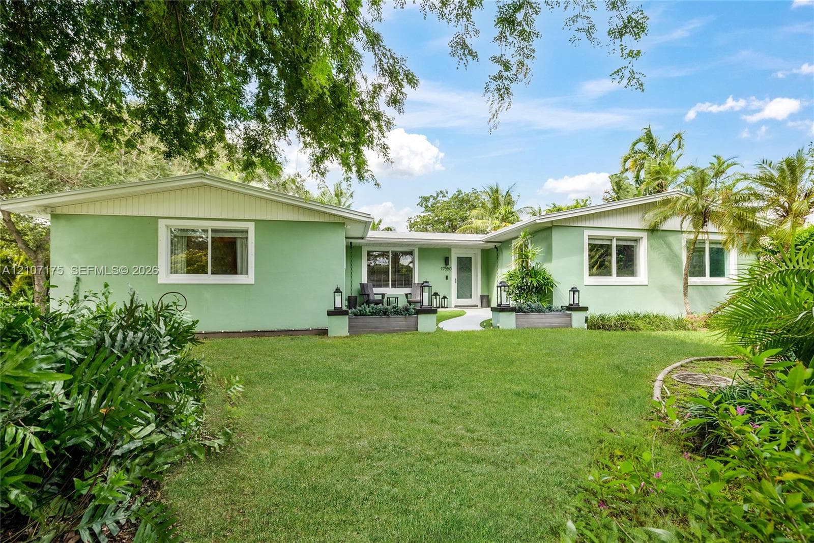 Single-story exterior featuring expansive manicured lawn, integrated concrete planters, and a paved walkway.