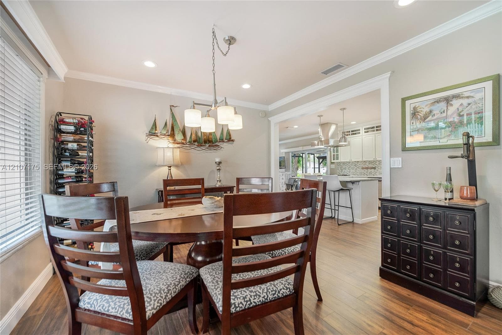 Dining space continues with wood-finish tile flooring, crown molding, and recessed lighting.