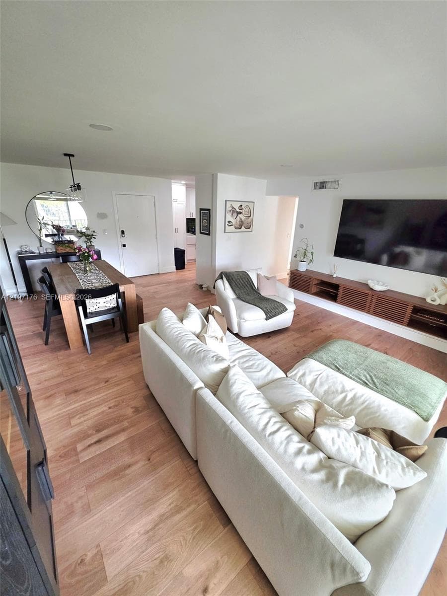 Open-concept living space featuring wood-finish flooring, recessed lighting, and a wall-mounted floating wood media console