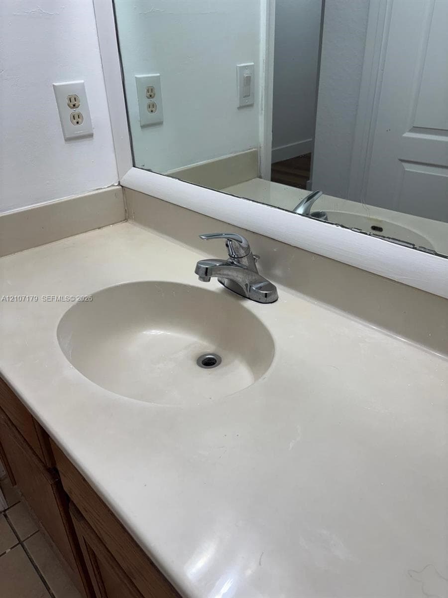 Integrated vanity featuring a solid-surface countertop with an inset basin, a single-handle chrome faucet, and a large-format mirror with a white trim frame