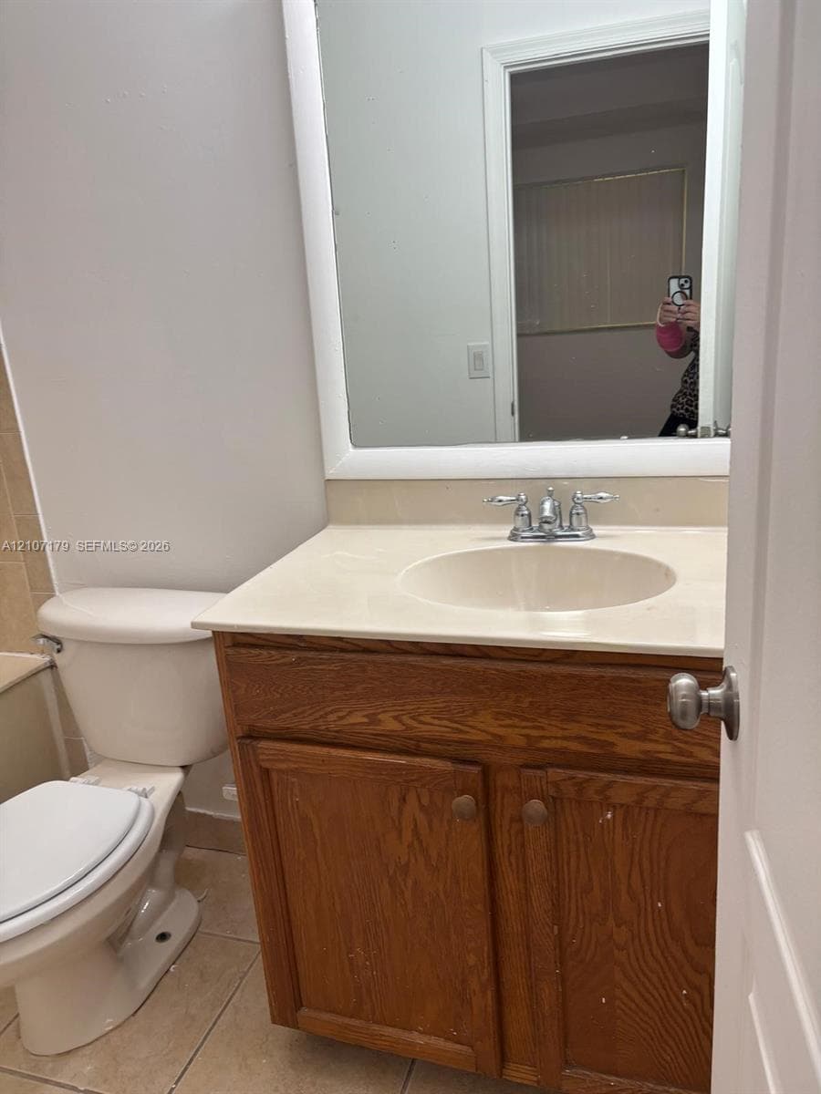 Wood-finish vanity cabinet featuring an integrated sink, solid surface countertop, chrome dual-handle faucet, and a large wall-mounted mirror