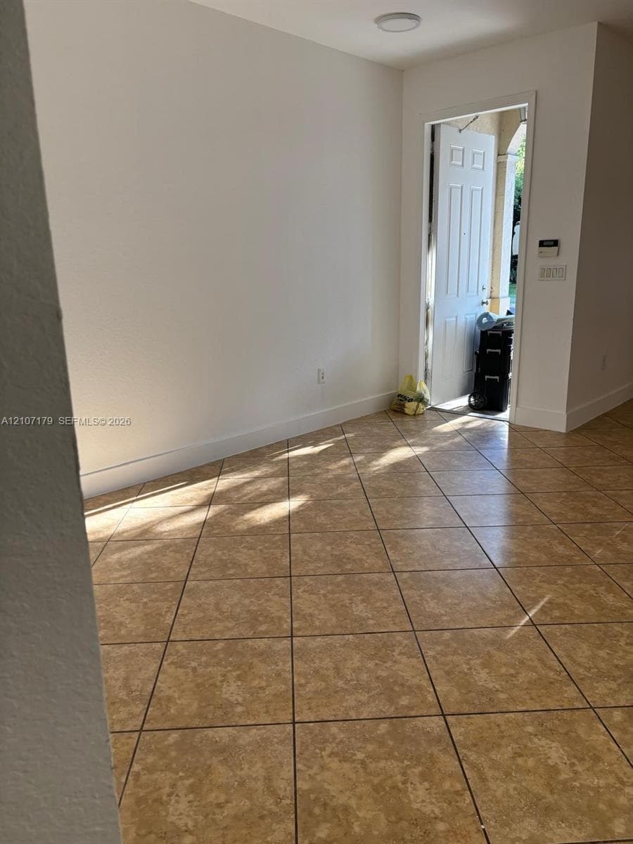 Interior space featuring square ceramic tile flooring, smooth wall finish, and a six-panel exterior entry door