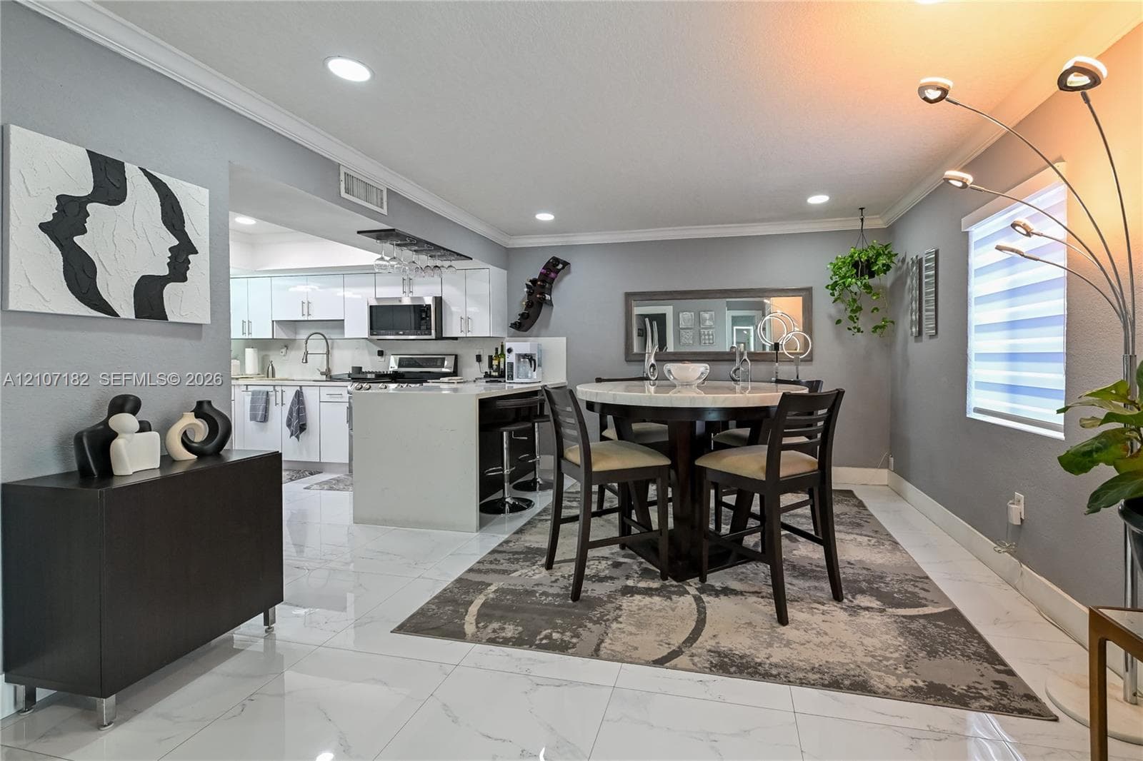 Large-format tile flooring, recessed lighting, crown molding, and white cabinetry with a built-in wine rack