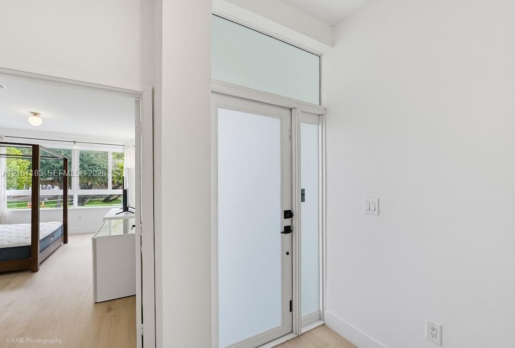 Entryway featuring a glass-panel door with frosted finish, transom window, and wood-finish flooring