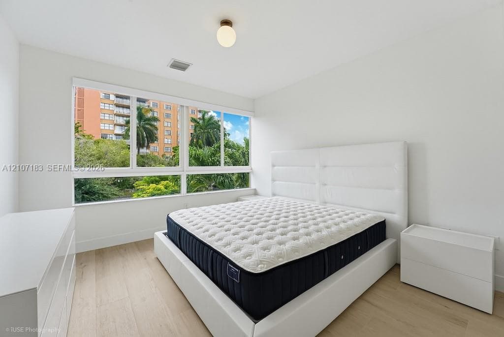 Floor-to-ceiling multi-panel windows, light-toned wood-finish flooring, and a modern globe flush-mount light fixture