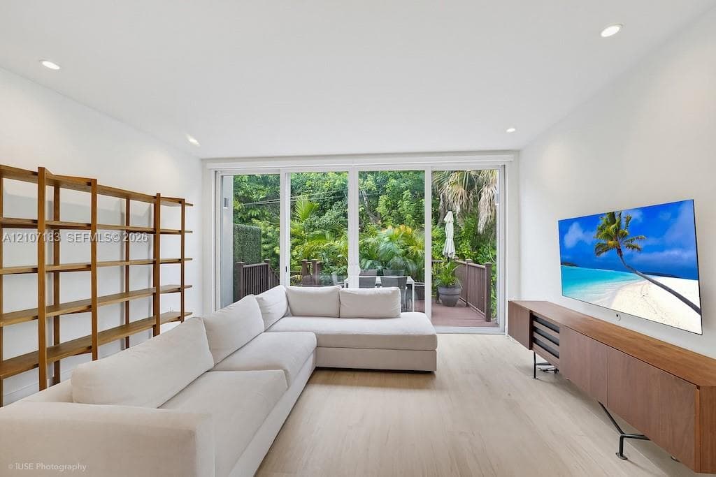 Bright, light-filled living space with expansive multi-panel glass doors opening to outdoor terrace and landscaped grounds