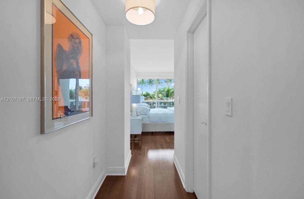 Hallway featuring wood-finish flooring, a drum-style overhead light fixture, and a full-height closet door