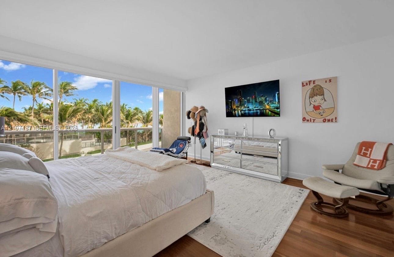 Floor-to-ceiling sliding glass panels, balcony access, wood-finish flooring, and expansive natural light