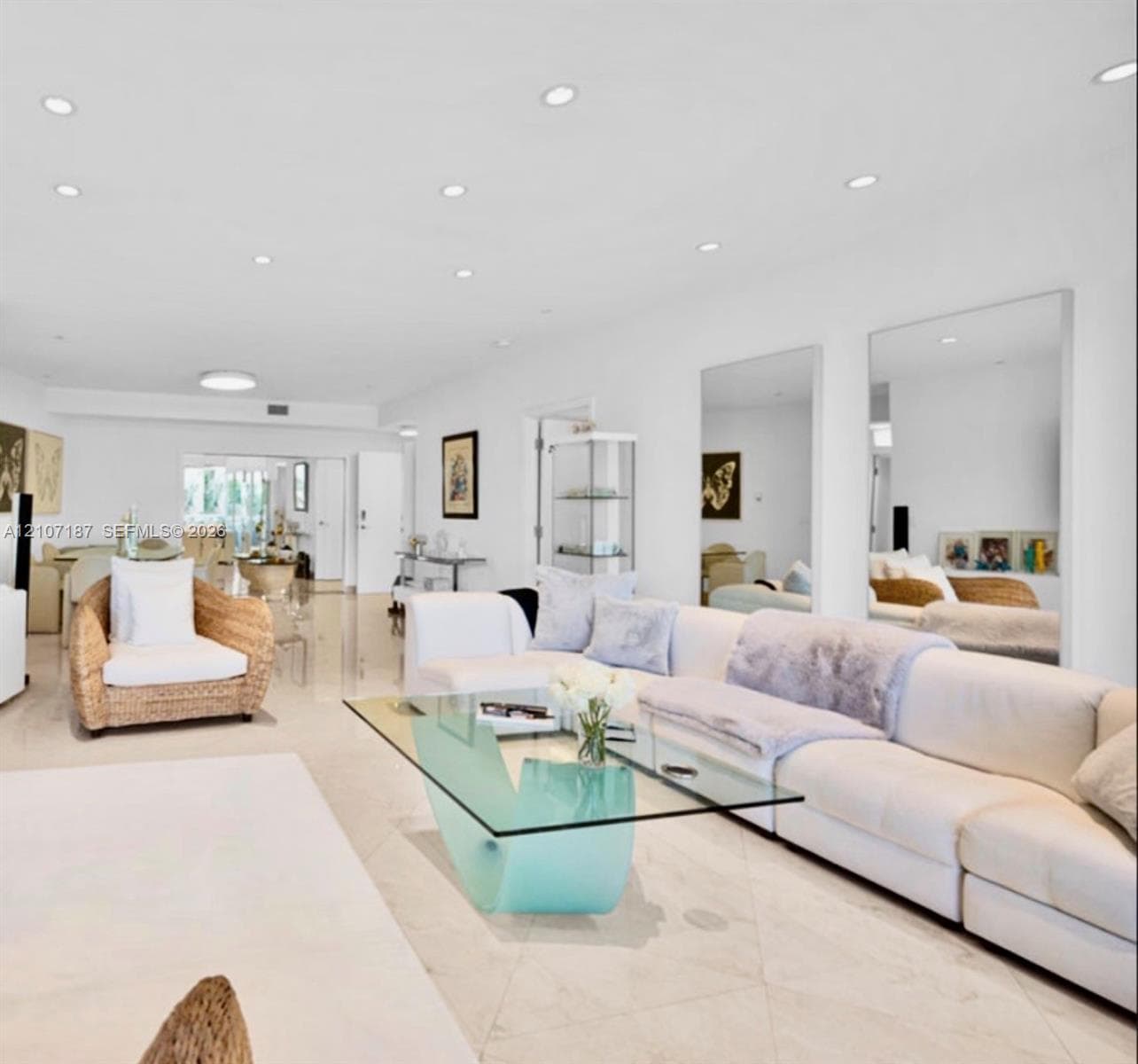 Open-concept living space featuring high-gloss tile flooring, recessed lighting, and large wall-mounted mirrors