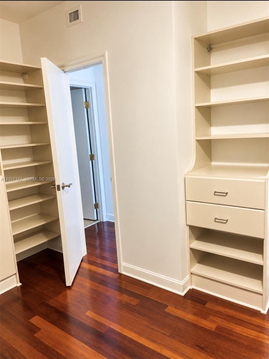 Custom built-in storage with adjustable shelving, two integrated drawers, and wood-finish flooring