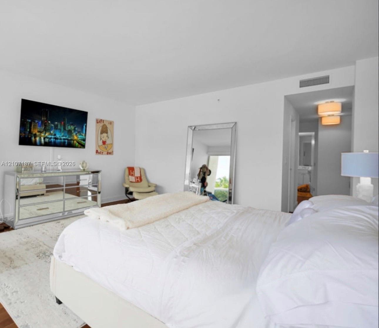 Neutral-toned interior space featuring wood-finish flooring, crisp white walls, and a recessed ceiling lighting fixture